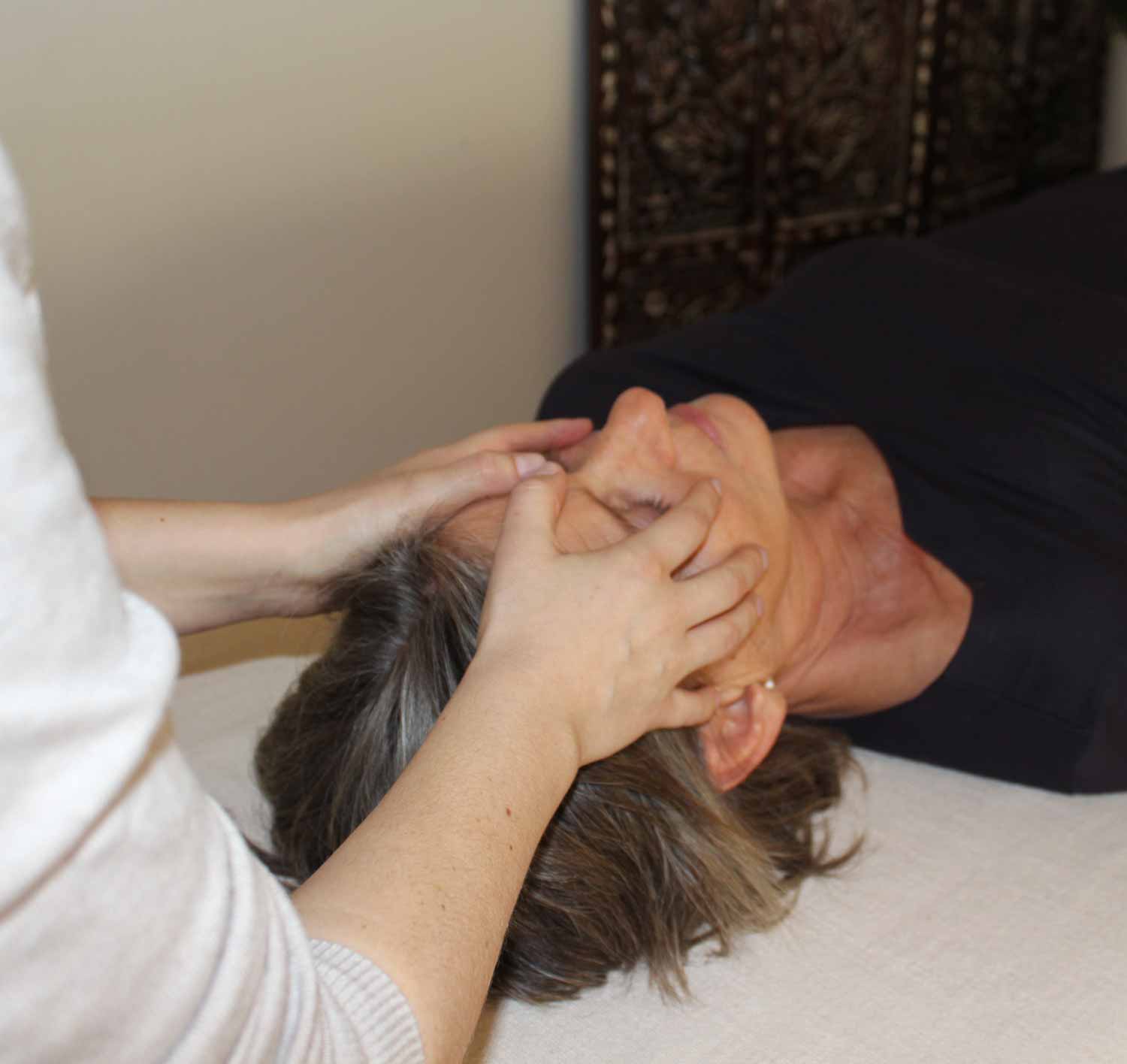 Craniosacral treatment underway. Therapist gently touches clients face